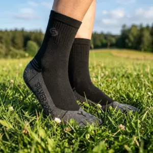 Skarpety antybakteryjne Athletic Silver - zbliżenie z boku na stopy w dwukolorowym modelu z czarnym prążkowanym ściągaczem i szarą stopą, widoczny napis SILVER SOCKS oraz litera L na palcach - osoba stojąca na zielonej trawie w plenerze.