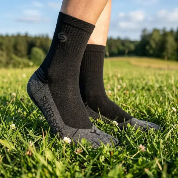 Skarpety antybakteryjne Athletic Silver - zbliżenie z boku na stopy w dwukolorowym modelu z czarnym prążkowanym ściągaczem i szarą stopą, widoczny napis SILVER SOCKS oraz litera L na palcach - osoba stojąca na zielonej trawie w plenerze.