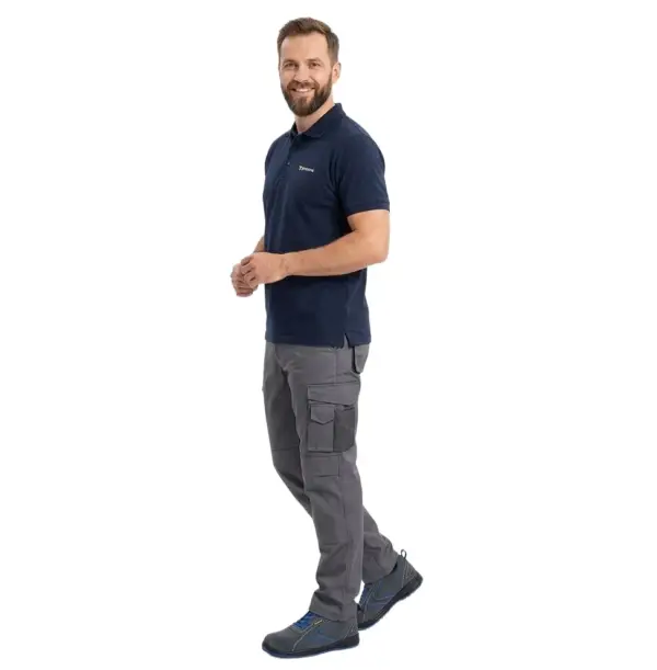 Szaro-niebieskie półbuty robocze GOBI S1 zaprezentowane na uśmiechniętym modelu w granatowej koszulce polo i szarych spodniach roboczych, ujęcie całej sylwetki z boku w pozie imitującej krok, wycięte na białym tle studyjnym.
