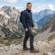 Półbuty Virginia O2 na stopach uśmiechniętego mężczyzny z plecakiem, ujęcie całej sylwetki
