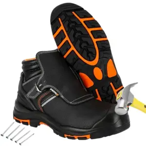 buty trekkingowe mont blanc - czarne z pomarańczowymi detalami, jeden but stoi z młotkiem uderzającym w podnosek, drugi oparty ukazuje podeszwę, obok leżą gwoździe - wycięte na białym tle studyjnym