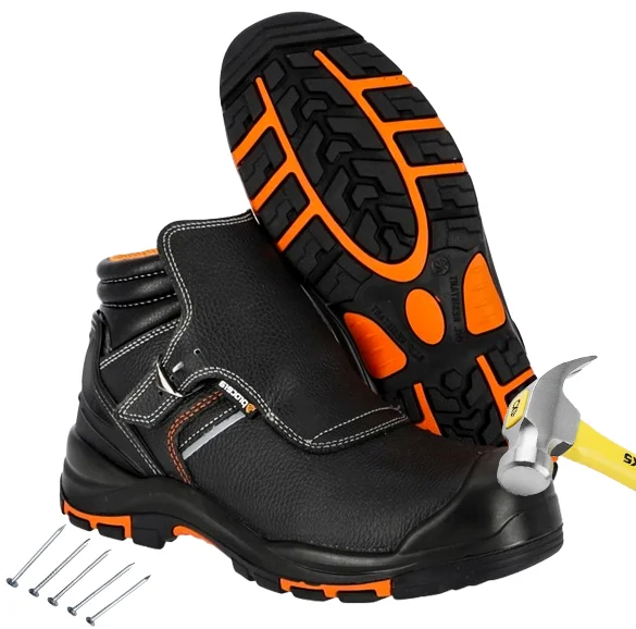 buty trekkingowe mont blanc - czarne z pomarańczowymi detalami, jeden but stoi z młotkiem uderzającym w podnosek, drugi oparty ukazuje podeszwę, obok leżą gwoździe - wycięte na białym tle studyjnym